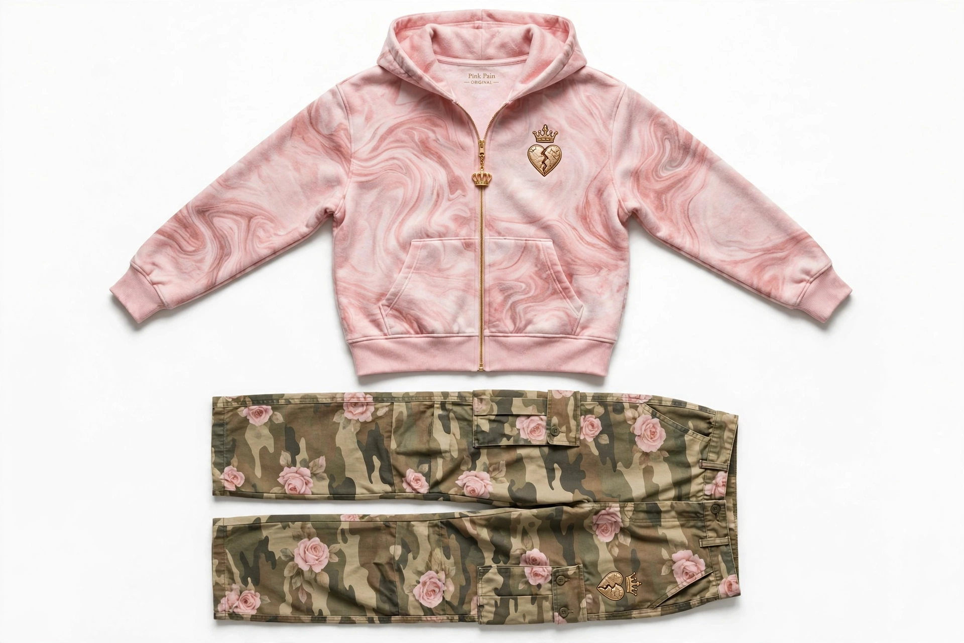 Pink Pain fleece set — pink marbled-fleece zip hoodie with gold crown-over-cracked-heart chest embroidery and a crown charm on the zipper, with camo cargo pants woven with pink roses